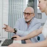 two nonprofit employees collaborating in front of a desktop.