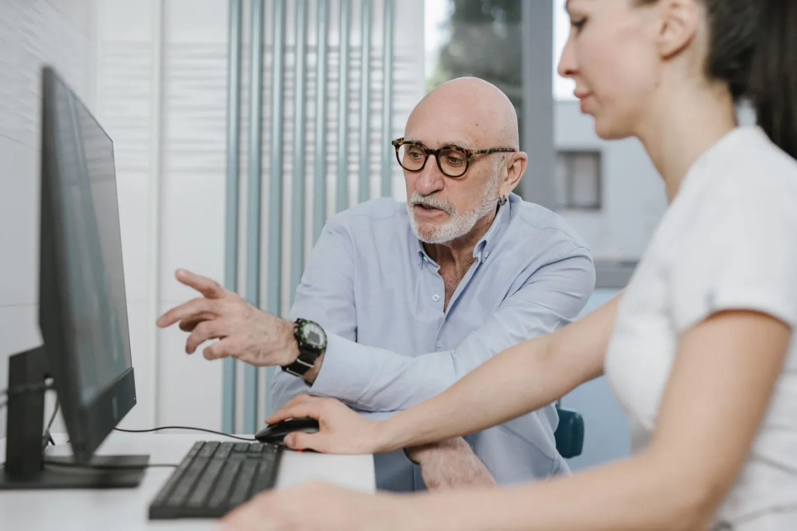two nonprofit employees collaborating in front of a desktop.