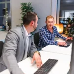 men collaborating in front of computers in an office.